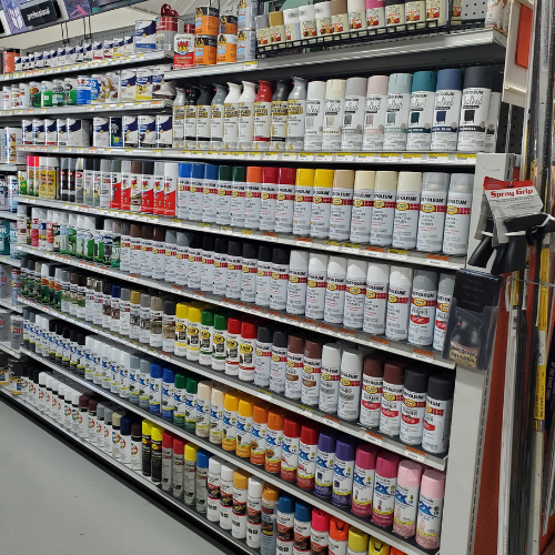 Shelf filled with various spray paint cans, organized in rows by color. Bright labels and colorful caps create a vibrant, organized display.