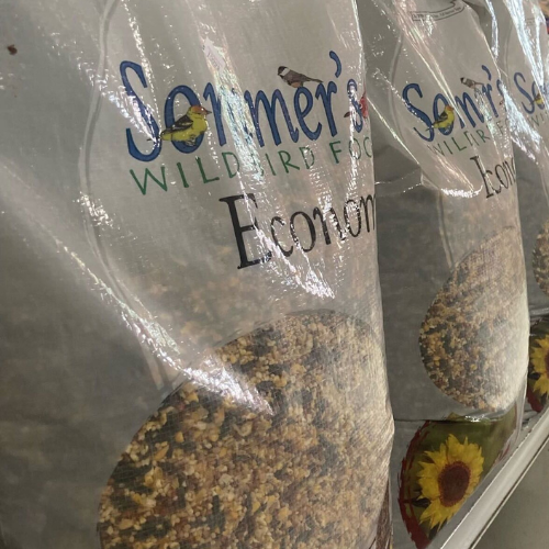 Bags of bird seed on a store shelf, labeled 